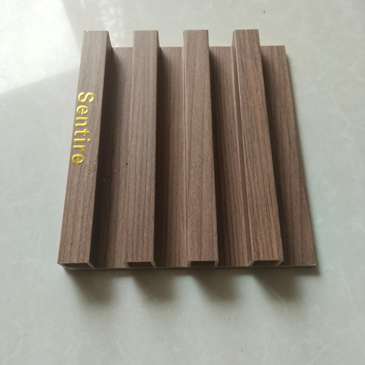 sentire wood slat wall panel sample in light walnut finish with gold sentire brand logo, WPC fluted interior wall panel
